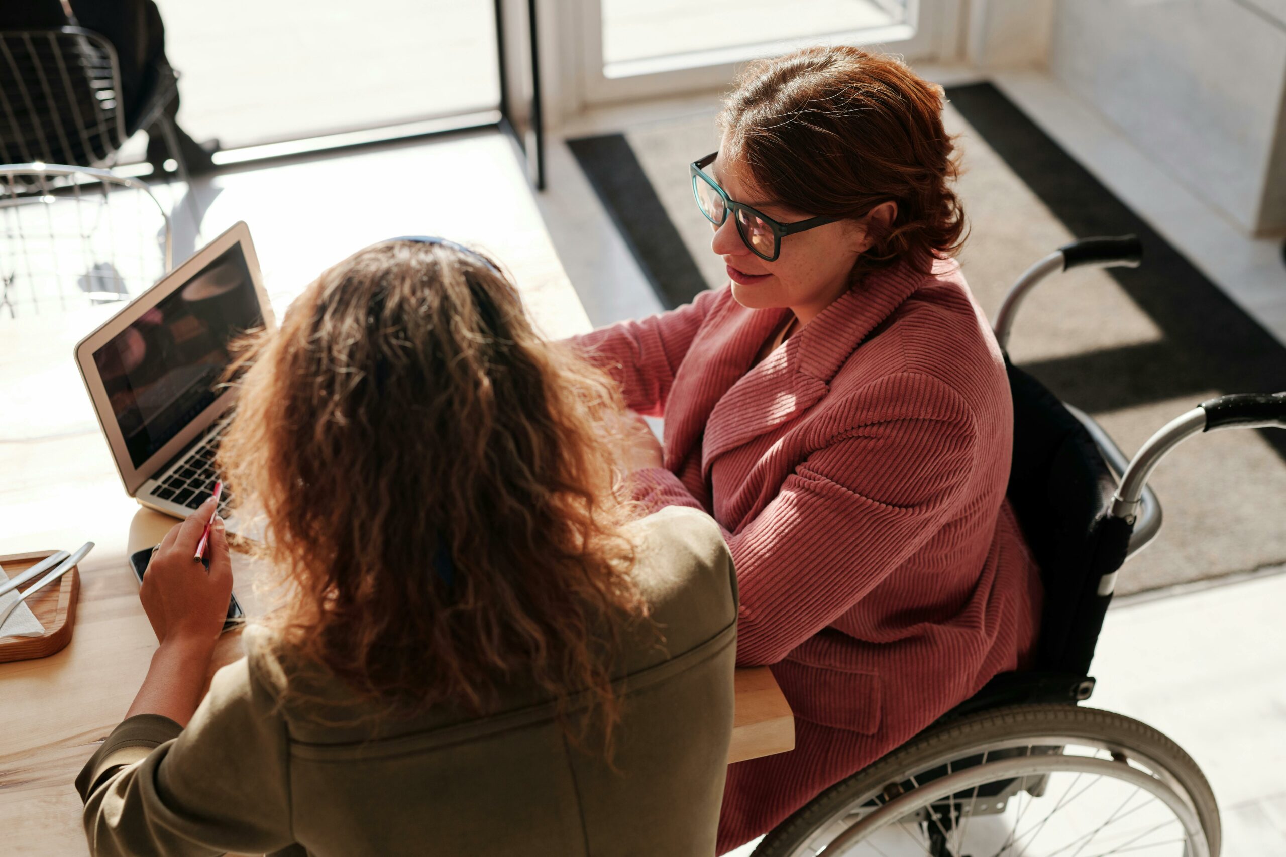     wheelchair user sitting next to person at a desk